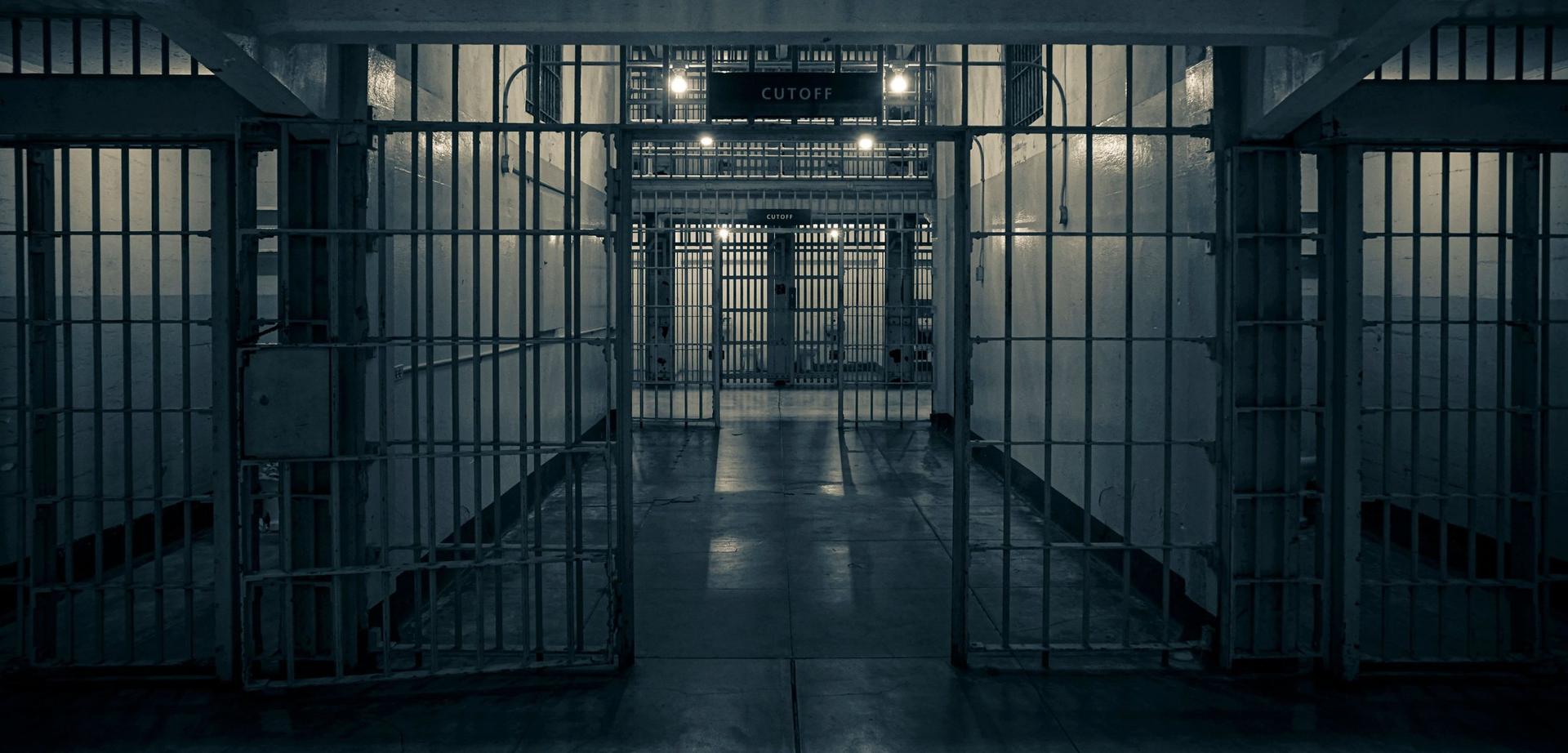 An empty prison corridor seen through barred gates